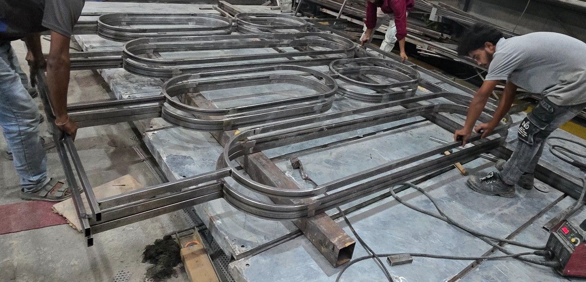 IronEdge team assembling repeating capsule-shaped metal frames for a glass partition