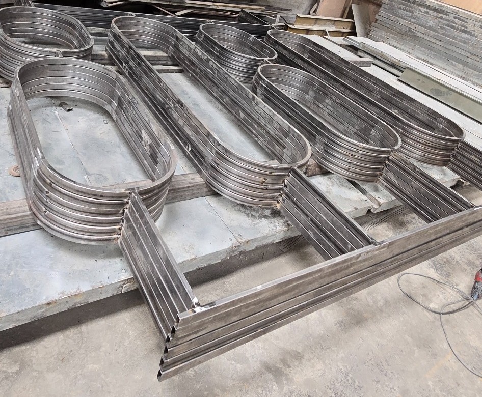 Workers fabricating a batch of repeating metal partition modules